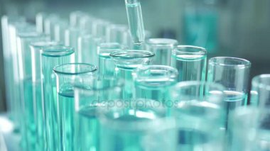 Bir laboratuarda, pipetli bir bilim adamı test tüplerindeki DNA ve molekülleri ayırmak için mavi bir sıvıyı analiz eder. Sıvıyla çalışan doktor..