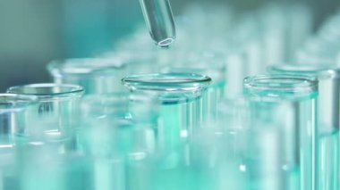Bir laboratuarda, pipetli bir bilim adamı test tüplerindeki DNA ve molekülleri ayırmak için mavi bir sıvıyı analiz eder. Sıvıyla çalışan doktor..