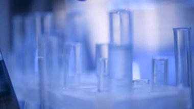 Bir laboratuarda, pipetli bir bilim adamı test tüplerindeki DNA ve molekülleri ayırmak için mavi bir sıvıyı analiz eder. Sıvıyla çalışan doktor..