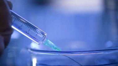 Bir laboratuarda, pipetli bir bilim adamı test tüplerindeki DNA ve molekülleri ayırmak için mavi bir sıvıyı analiz eder. Sıvıyla çalışan doktor..