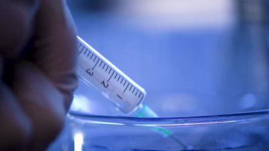 Bir laboratuarda, pipetli bir bilim adamı test tüplerindeki DNA ve molekülleri ayırmak için mavi bir sıvıyı analiz eder. Sıvıyla çalışan doktor..