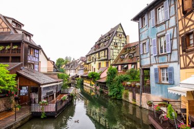 Kanal ve renkli evler Petite Venedik, Colmar, Fransa. Bulutlu günde Köprüsü'nden görüntülemek.