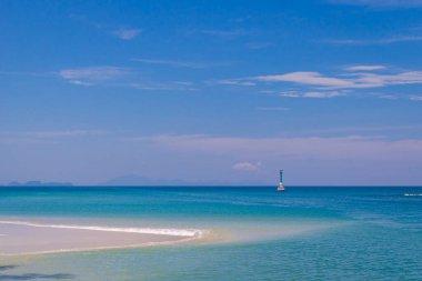 Mavi gökyüzünde pürüzsüz kum ve ışık feneriyle turkuaz deniz