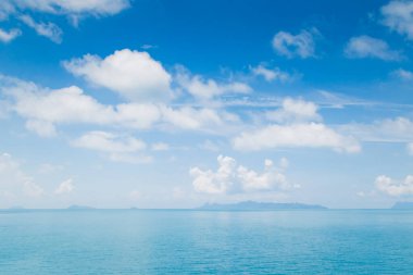 Mavi gökyüzünde beyaz kabarık bulutlar ve turkuaz deniz