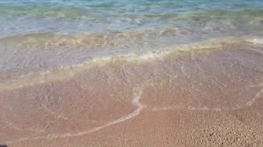 Kristal berraklığında su üzerinde yumuşak dalgalar ile altın kum plaj