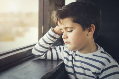 Bir pencere yanında üzgün çocuk