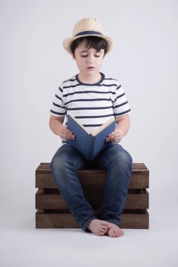 Çocuk bir ahşap kutu içinde oturan bir kitap okumak