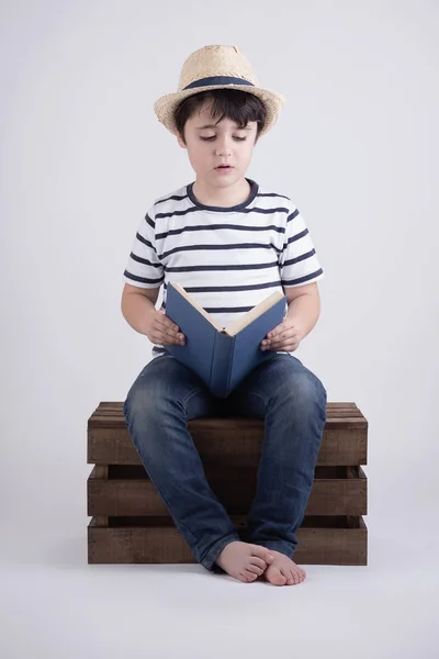 Мальчик читал книгу сидя в деревянном ящике — стоковое фото