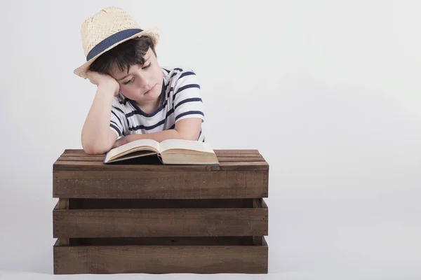Menino ler um livro sentado em uma caixa de madeira — Fotografia de Stock