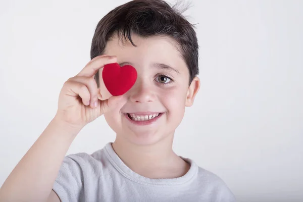 Niño juguetón cubriendo su ojo con corazón — Foto de Stock