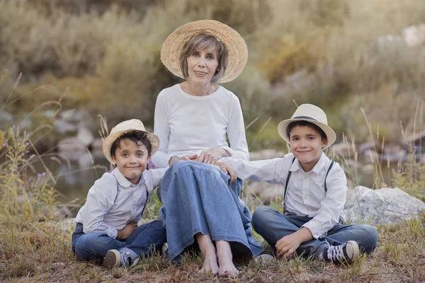 Grandmother with her grandchildren sitting in the field — Stock Photo, Image