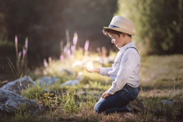 Marzycielski chłopiec siedzi w polu — Zdjęcie stockowe