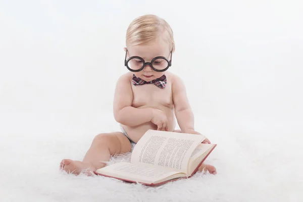 Маленький счастливый ребенок читает книгу в очках и галстуке — стоковое фото
