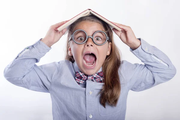 Dziewczyna krzyczy z książką na głowie, powrót do szkoły — Zdjęcie stockowe
