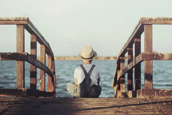 Застенчивый мальчик, смотрящий на море — стоковое фото