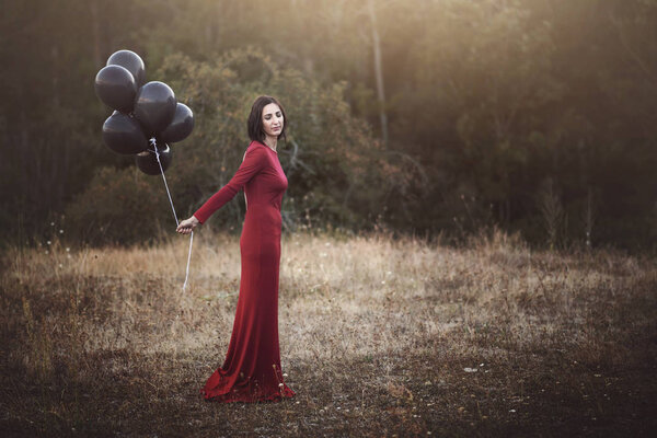 Pensive woman with balloons in the field