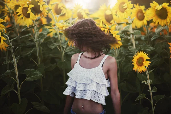 Flicka i fält av solrosor — Stockfoto