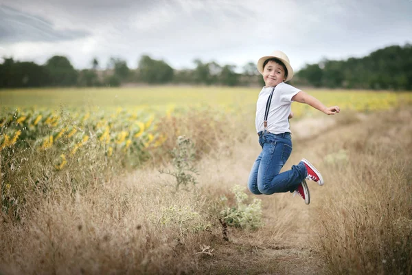 Usměvavý chlapec skákání v poli — Stock fotografie
