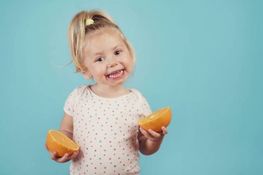 mavi arka plan üzerinde bir portakal ile gülümseyen bebek