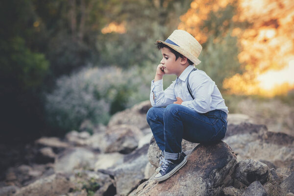 thoughtful child sitting on a rock