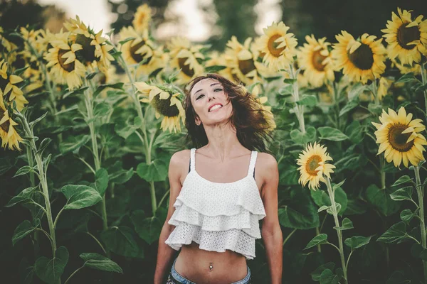 Ung kvinna i solrosfält — Stockfoto