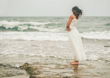 Sahilde dalgın genç bir kadının arka görüntüsü