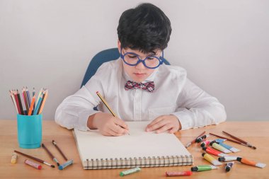 çocuk beyaz arkaplanda bir tablo çiziyor