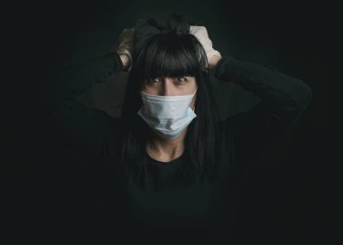 Coronavirus, tıbbi maske takan genç bir kadın siyah arka plan yüzünden karantinaya alınmayı bekliyor.