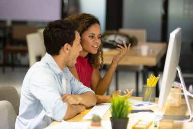 Bilgisayar üzerinde çalışan iki genç iş arkadaşı, proje üzerinde birlikte çalışıyorlar..