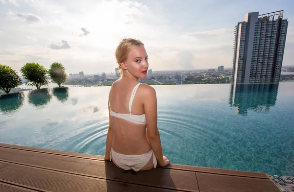 Young woman white bikini enjoying a sun, Slim young girl model in white bikini  by the pool.