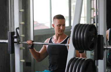 Kafkasyalı yakışıklı genç bir adam ve spor kıyafetleri içinde kaslı. Spor salonunda egzersiz yaparken ağırlık kaldıran genç bir adam. Sağlıklı spor yaşam tarzı, spor konsepti. Metnin için kopyalama alanı ile.