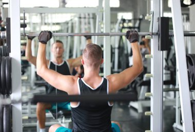 Kafkasyalı yakışıklı genç bir adam ve spor kıyafetleri içinde kaslı. Spor salonunda egzersiz yaparken ağırlık kaldıran genç bir adam. Sağlıklı spor yaşam tarzı, spor konsepti. Metnin için kopyalama alanı ile.