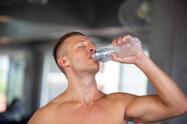 Spor salonundaki egzersiz dersinde sağlıklı, beyaz, yakışıklı bir genç adam ve büyük kaslı, içme suyu. Sağlıklı spor yaşam tarzı, spor konsepti. Metnin için kopyalama alanı ile.