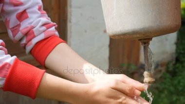 Bir kadın eski bir banyoya altında ellerini yıkar