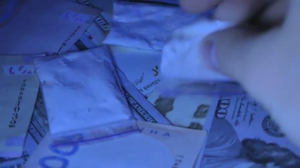 Droger och cash pengar överallt på ett bord. Närbild skott. Ultraviolett ljus — Stockvideo