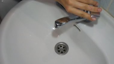 Kirli musluk suyu. Musluk suyu lavaboda akıyor, kirli, paslı, altın rengi kahverengiyle başlıyor..