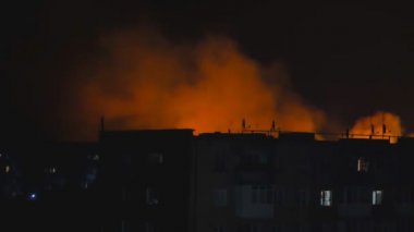 Ukrayna, şehirde gece yangını, bir evin siluetinin arka planında. Yangın felaketi ve kaza trajedisi konsepti.