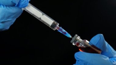 Doktorlar ellerinde şırınga ve kırmızı aşı şişesi tutuyor. Hastanenin arka planında. Sağlık ve tıbbi kavramlar.