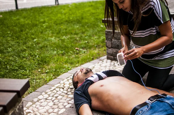 Girl applying defibrillator electrodes for CPR with defibrillator — Stock Photo, Image