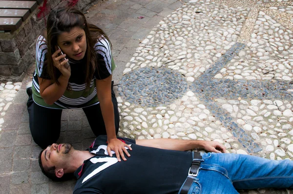 Chica llamando al servicio de emergencia para un hombre inconsciente — Foto de Stock