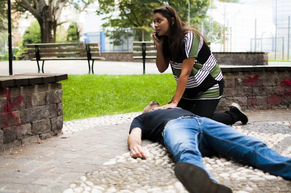 Chica llamando al servicio de emergencia para un hombre inconsciente — Foto de Stock