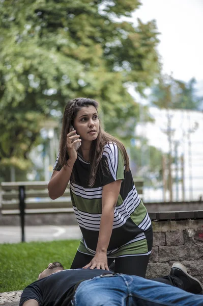 Chica llamando al servicio de emergencia para un hombre inconsciente — Foto de Stock