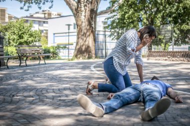 girl calling emergency service to assist a guy with cpr clipart