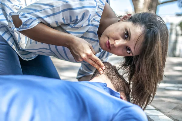 Girl checking vital parameters of an unconscious guy after heart attack — Stock Photo, Image