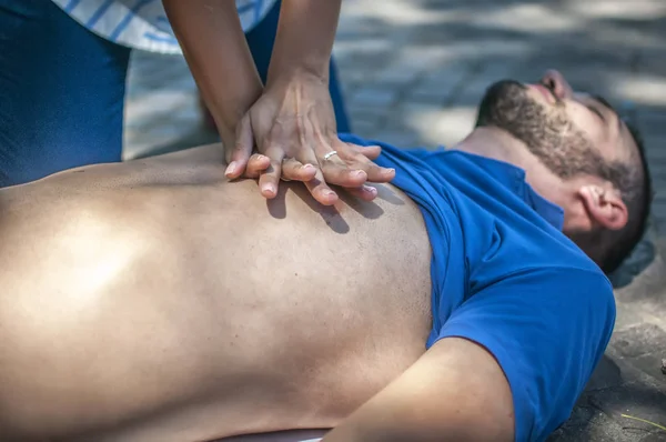 Girl making cardiopulmonary resuscitation to an unconscious guy after heart attack — Stock Photo, Image