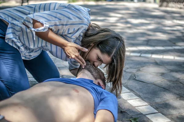 Lány segít egy eszméletlen fickó, a száj szájba újraélesztést és a cpr — Stock Fotó