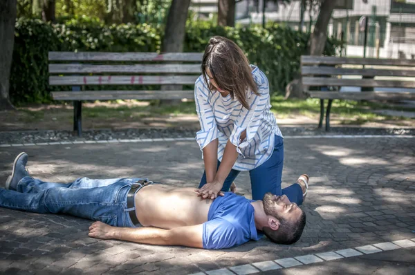 Girl making cardiopulmonary resuscitation to an unconscious guy after heart attack — Stock Photo, Image