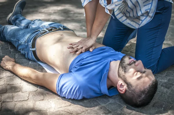 Girl making cardiopulmonary resuscitation to an unconscious guy after heart attack — Stock Photo, Image