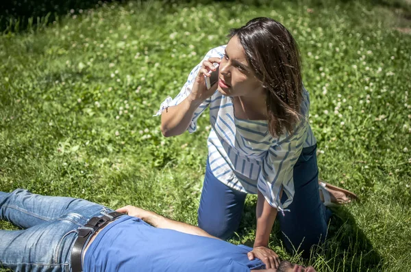 Menina chamando o serviço de emergência para um cara inconsciente — Fotografia de Stock