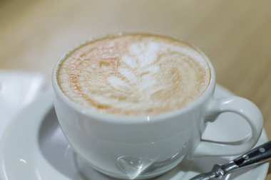 Kahve kapuçino beyaz Kupası ve bir kafede masada beyaz cep telefonu.